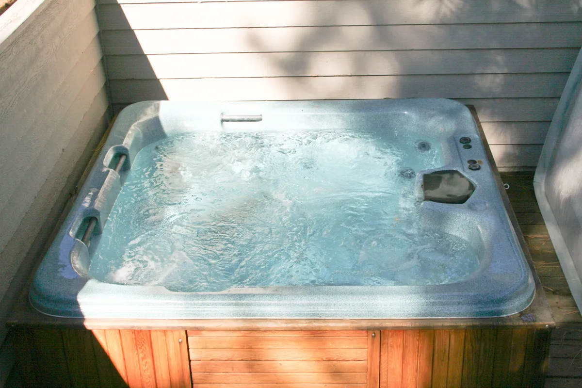 A sparkling indoor hot tub set in a tranquil, softly lit indoor space. The inviting water and cozy atmosphere suggest a perfect spot for relaxing after a day of outdoor exploration, reinforcing the idea of returning home to comfort after adventure.