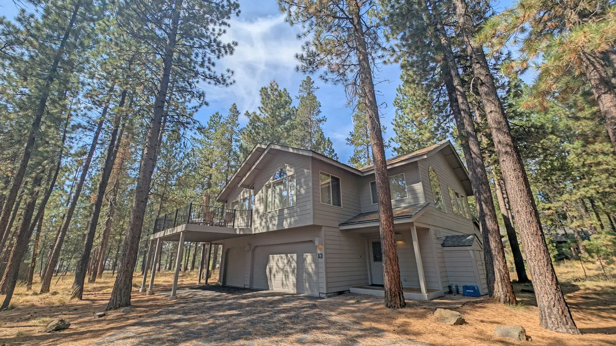 The home’s modern exterior and deck are nestled among tall pine trees, with ample space for outdoor lounging and socializing. The view captures both the architecture and the surrounding peaceful environment, inviting guests to relax and enjoy the natural beauty of Sunriver.