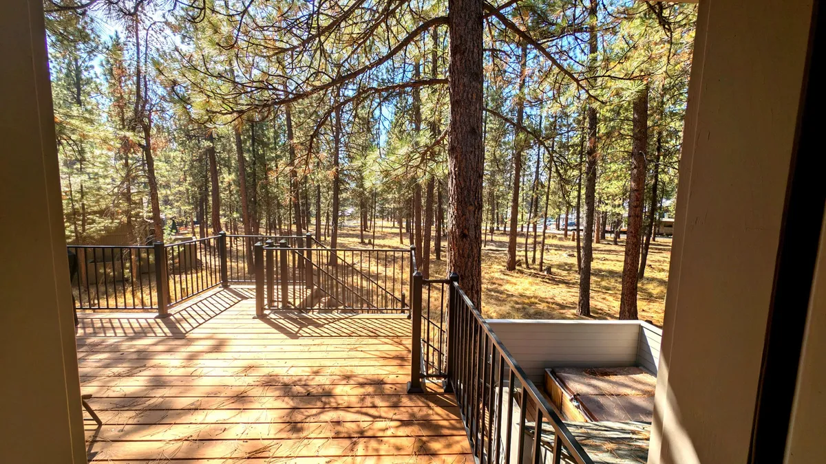 A peaceful outdoor deck set amid tall trees, with open space and comfortable seating. The scene exudes tranquility and invites guests to relax, read, or simply enjoy the natural beauty and sunset views after a day of exploration.